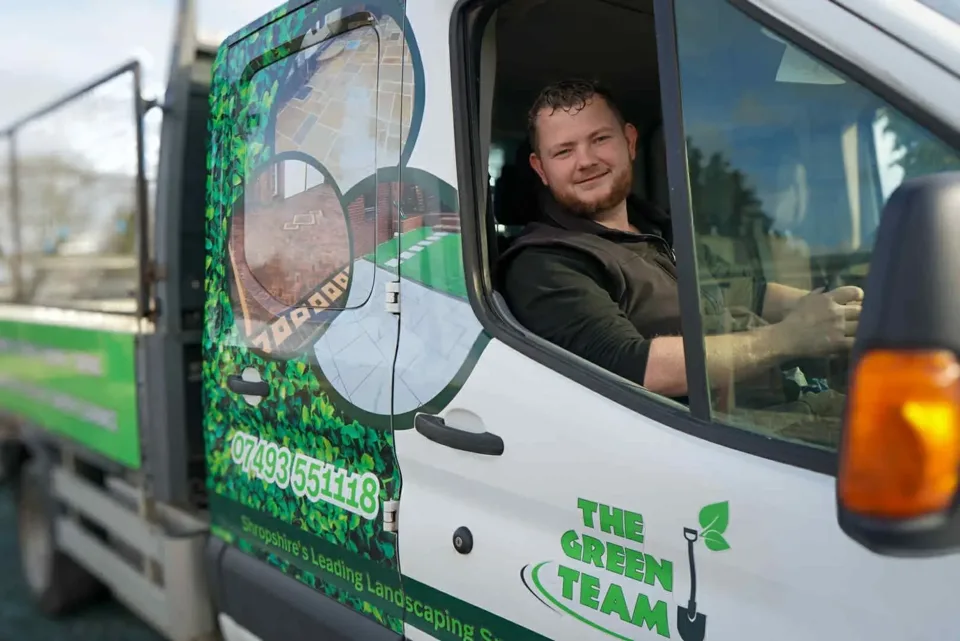 Mike, owner of The Green Team, smiling from the driver's window of a Green Team branded landscaping truck