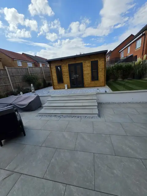 The same steps finished in porcelain with a rendered wall, decorative stone and a garden room beyond